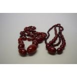 Two 'cherry amber' bead necklaces, of fifty-nine graduated oval beads, largest approx 40mm wide,