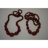 Two 'cherry amber' bead necklaces, of fifty-five graduated oval beads,