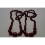 Two 'cherry amber' bead necklaces, of forty-nine graduated oval beads,