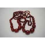 Two 'cherry amber' bead necklaces, of seventy-nine graduated oval beads,