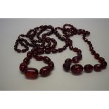 Two 'cherry amber' bead necklaces, of sixty-seven facetted and graduated oval beads,