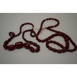 Two 'cherry amber' bead necklaces, of fifty-seven graduated oval beads,