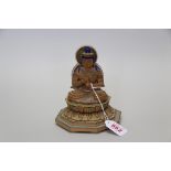 An eastern carved wood Buddha on lotus leaf stand, with painted decoration, 15cm high.