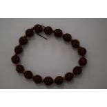 A carved and pierced nut bead necklace, of eighteen spherical beads.