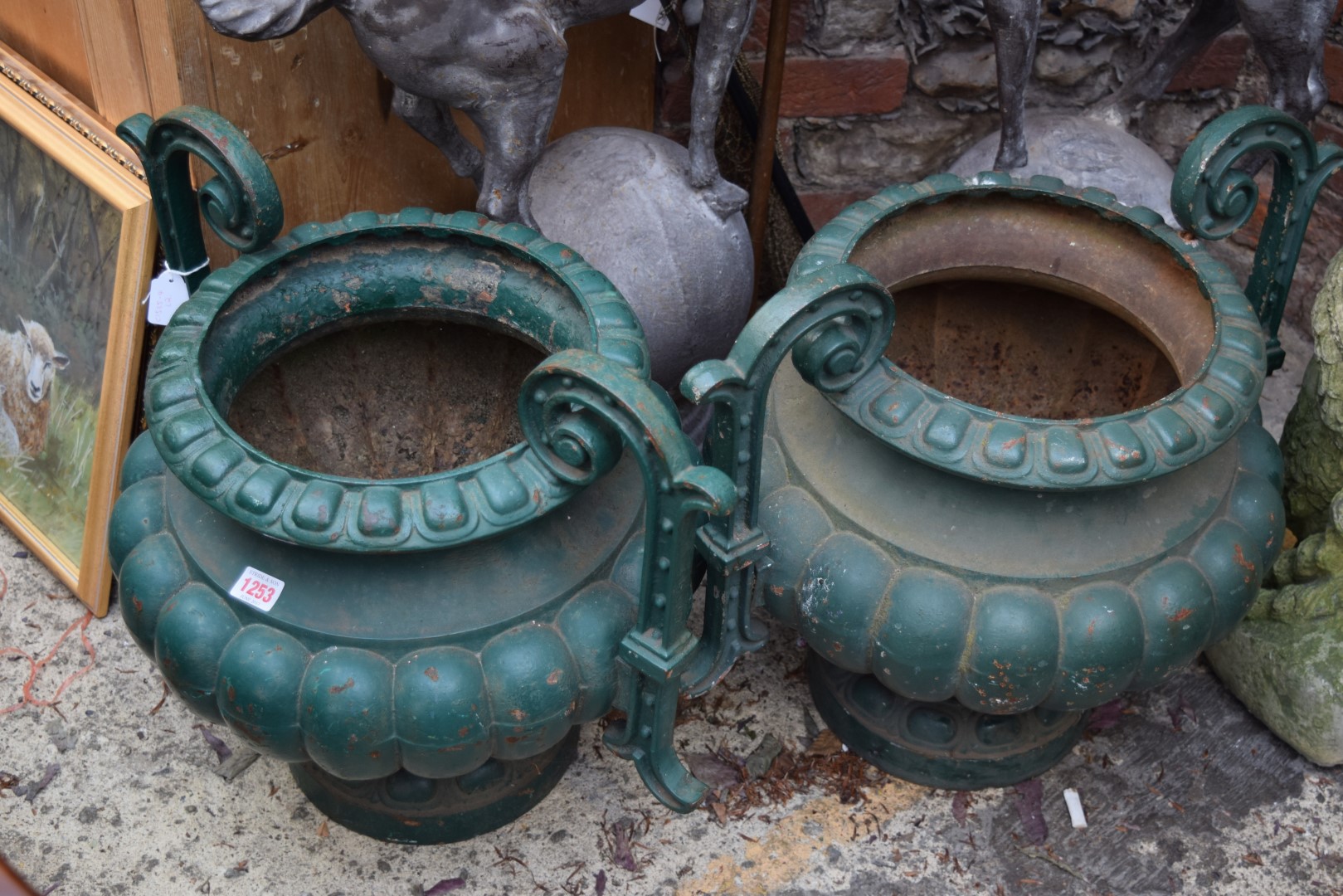 A pair of antique green painted cast iron twin handled urns, 48.5cm high.