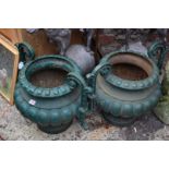 A pair of antique green painted cast iron twin handled urns, 48.5cm high.