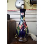 A Moorcroft vase form lamp, tubelined with orchids and other flowers against a blue ground,