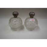 A pair of hobnail cut glass scent bottles, having silver lids.