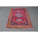 A North West Persian triple medallion rug on a red field, 151 x 105cm.
