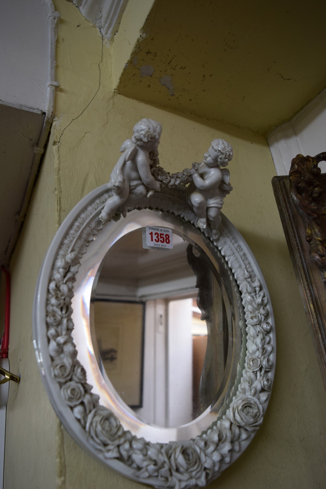 A Sitzendorf blanc de chine oval wall mirror, with cherub surmount, 33cm high.