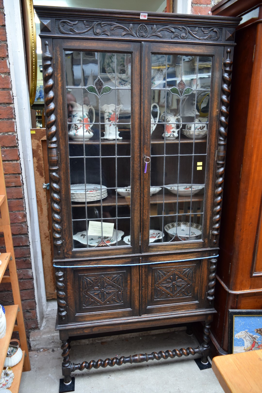 An early 20th century carved oak and leaded glass bookcase, labelled 'Merryweather & Son, Holloway,