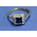 A 9ct gold ring set an emerald cut sapphire surrounded by white sapphires.
