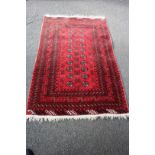 An Afghan rug, with two by ten Gul design, on a red field, 164 x 102cm.