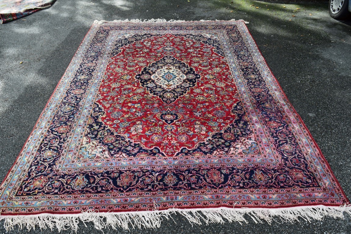 A Persian 'Kashan' carpet, with large coastal medallion on a floral red field, 352 x 251 cm.