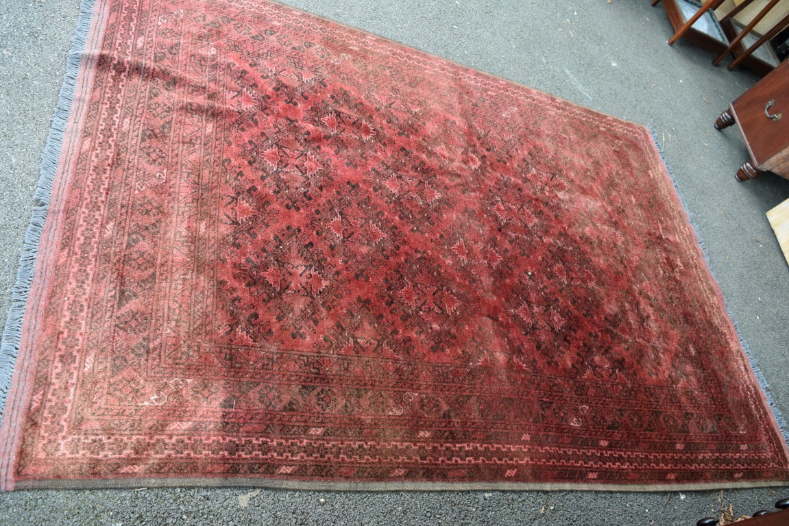 An Afghan carpet, with an all over diamond medallions on a red field,