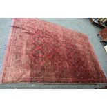 An Afghan carpet, with an all over diamond medallions on a red field,