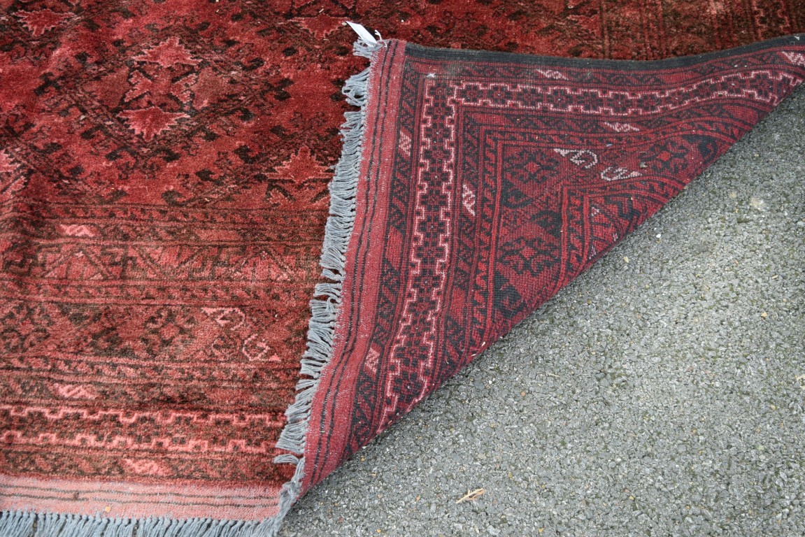 An Afghan carpet, with an all over diamond medallions on a red field, - Image 4 of 4
