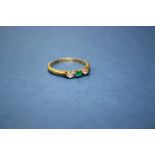 An 18ct gold ring set central emerald with diamond to each side.