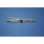 A 10k bar brooch set central garnet; together with an unmarked stick pin set diamond chips;