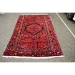 A Persian Hamadan rug, with central medallions on a geometric motif red field,