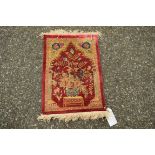 A small fine silk prayer mat, depicting a basket of flowers on a table beneath a prayer niche,
