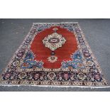 A North West Persian Tabriz carpet, with large central ivory medallion on a madder red plaid field,