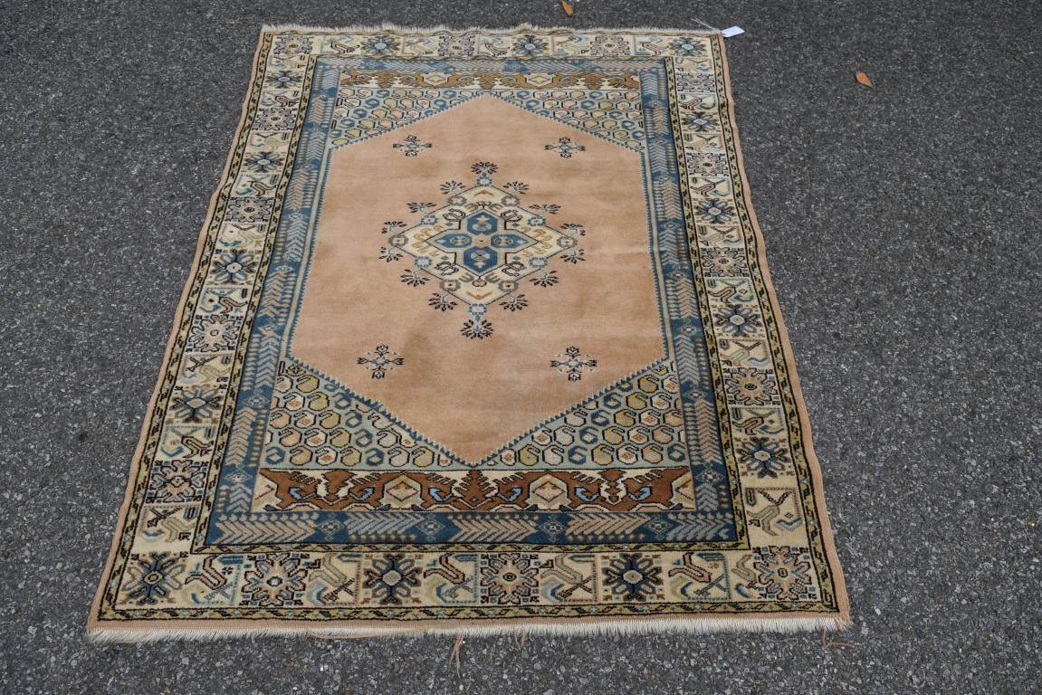 A Turkish rug, with central medallion on a salmon pink field, 150 x 115cm.