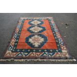 A Turkish carpet, with three large star medallions on a red field with ivory geometric border,