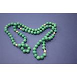 A green hardstone bead necklace interspersed with small baroque pearls.