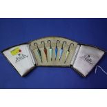 A cased set of six novelty silver and guilloche enamel umbrella cocktail sticks,