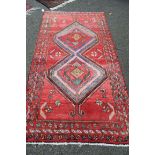 A Persian Hamadan rug, having two large medallions on red field. 210 x 113cm.