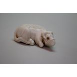 A Japanese carved ivory netsuke of a recumbent ox, Meiji period,