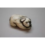 A Japanese carved bone netsuke of a puppy, late 18th/early 19th century, 4cm long.