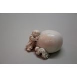 A Japanese carved ivory netsuke of two figures with a large persimmon, Meiji period, signed, 3.