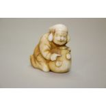 A Japanese carved ivory netsuke of a lady guarding a large sack or money bag, Meiji period,