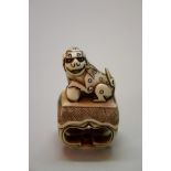 A Japanese carved ivory seal type netsuke of a shishi on a table, signed, 19th century, 4.5cm high.