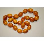 An amber necklace, of twenty two oval beads, 62cm long, 116g.