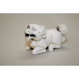 A Japanese carved ivory netsuke of a recumbent lion dog, signed, 5cm long.