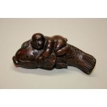 A Japanese carved hardwood netsuke of a boy on a carp, early 20th century,