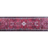 A PERSIAN RUNNER CARPET/RUG With a large white central flower held in a red field cartouche,