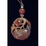 AN ANTIQUE ORIENTAL RED JADE AND SEED PEARL PENDANT Carved with an exotic fruit with pierced gnarled