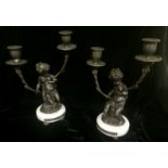 A PAIR OF 19TH CENTURY DESIGN BRONZE CANDELABRAS Modelled as seated Putti holding vines, raised on