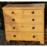 A VICTORIAN PINE CHEST OF DRAWERS Having an arrangement of two over three long drawers, raised on