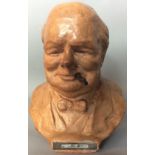 PETER LAMBDA, A WW11 TERRACOTTA POTTERY BUST/CIGAR LIGHTER OF SIR WINSTON CHURCHILL Having a brass