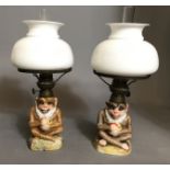 A PAIR OF LATE 19TH/EARLY 20TH CENTURY CONTINENTAL PORCELAIN FIGURATIVE OIL LAMPS Moulded as monkeys