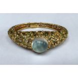 A HEAVY 18CT GOLD AND ENAMEL GEM SET BANGLE The hinged tapering bangle of pierced foliate design