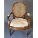 A WALNUT BERG?RE OPEN ARMCHAIR With rattan back and seat, upholstered armrests and acanthus leaf