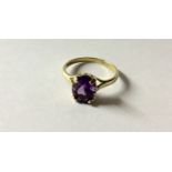 A HALLMARKED 9CT GOLD AND AMETHYST DRESS RING The oval cut amethyst claw set to trifurcated