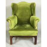 A GEORGE III MAHOGANY WING ARMCHAIR Upholstered in a green fabric, raised on square legs joined