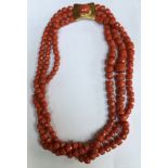 A TRIPLE STRAND CORAL BEAD NECKLACE The graduated facet cut barrel form beads strung on knotted